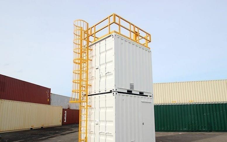 A yellow mobile confined space training container with a side door open, showing internal training elements.